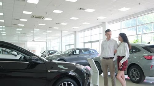 A Young Couple is Choosing a New Car at a Dealership Buying a Car on Credit