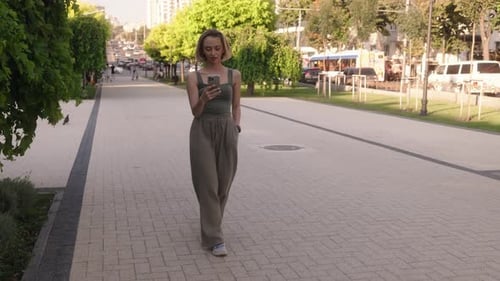 Young Woman Walks Down a City Sidewalk