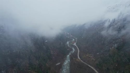 Misty Snowy Mountain Valley with River and Winding Road in Winter