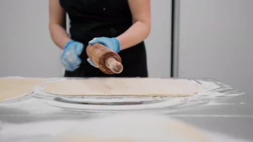 The kitchen in the bakery - the process of preparing cinnabons, the woman baker forms doughs