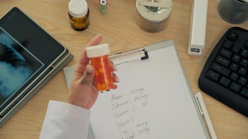 Doctor Holds Pill Bottle at Desk