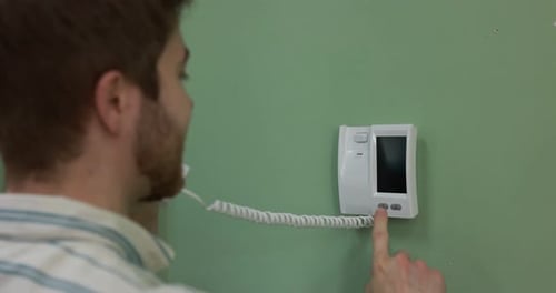 Man answering intercom call at home, closeup. Camera moving in