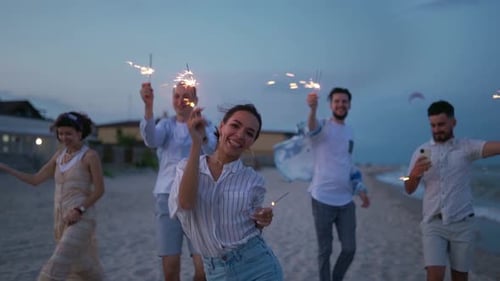 Friends Celebrate on Beach with Sparklers at Dusk