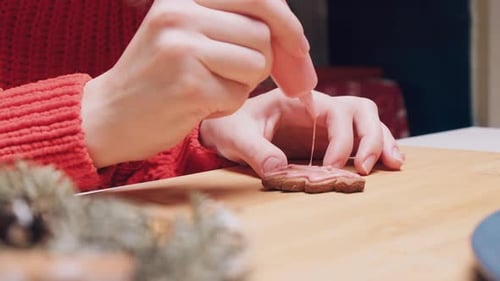 Closeup of Hands Painting Christmas Treeshaped Cookies with Pink Cream