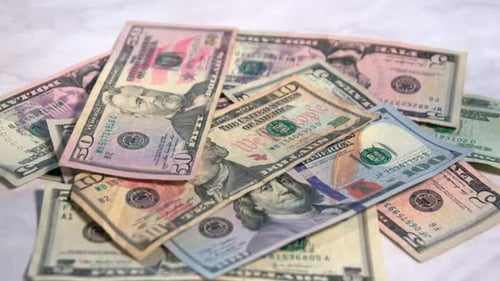 American money falling onto a marble countertop.