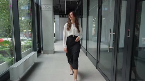 A Business Woman is Walking Down a Corridor in an Office Center