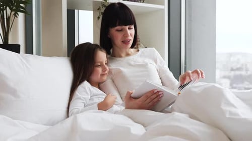 Woman Reads Bedtime Story to a Child in Bed