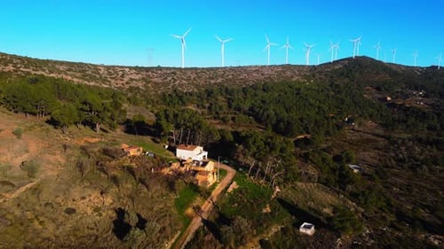 Aerial drone footage of a wind turbines on mountain ridges generating renewable energy.
