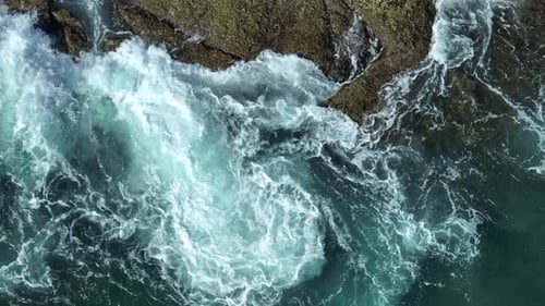 Rough ocean waves splashing against rocky shore.