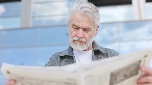 Senior Man Reading Newspaper Outdoors