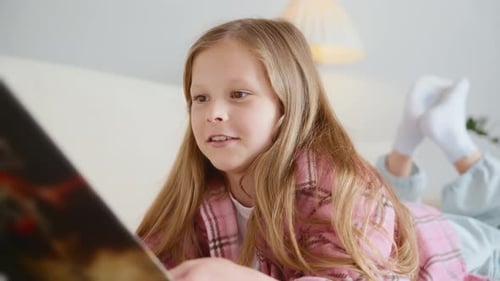 Girl Smiling While Reading on Bed