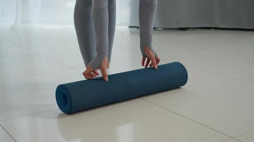 Young Adult Unrolls Yoga Mat for Workout