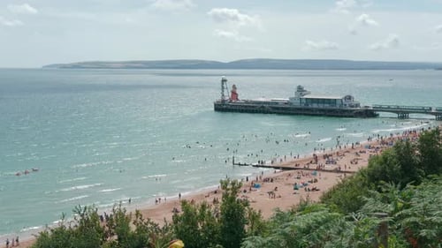 Tourists Having Vacation At Bournemouth Beach And Pier During Summer In Dorset, United Kingdom. high