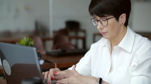 Attraktive reife Geschäftsfrau, die im Büro oder Coworking am Laptop arbeitet