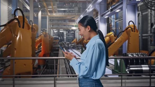 Woman Using Phone in Modern Factory with Robots