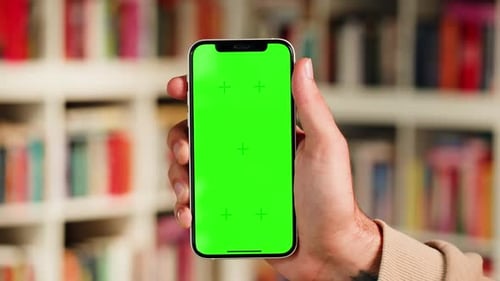 Man Holding Phone with Chroma Key Screen in University Library Reading Smartphone Application in