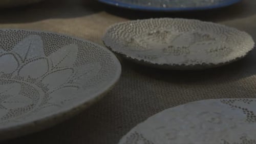 high quality colorful clay plates at artisan market with moving foliage shadows