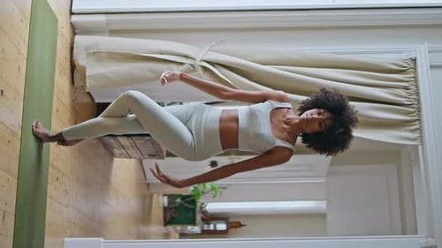 Modèle mince pratiquant le yoga, les asanas au tapis, une femme africaine Namaste pose verticalement