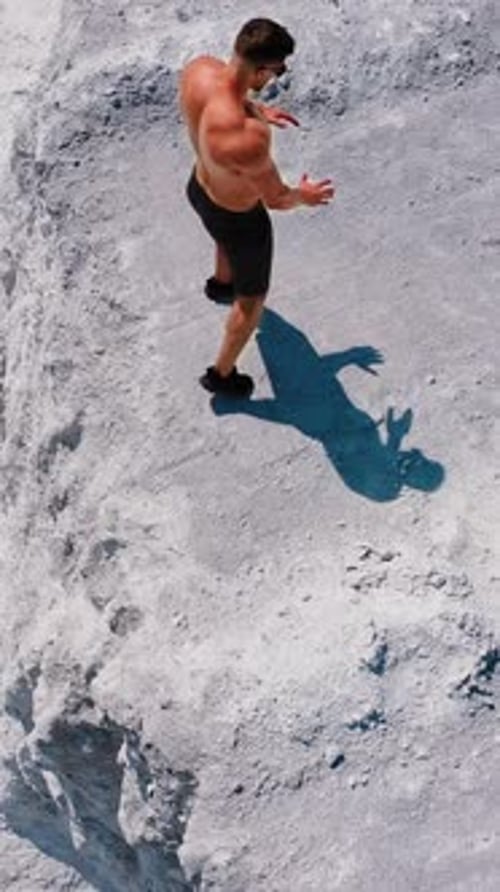 Man Stands Shirtless on Light Rock Ridge, Aerial View