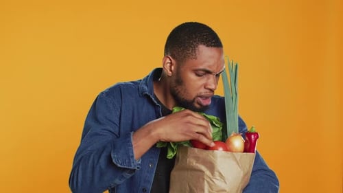 Young Adult Inspects Bag of Fresh Vegetables