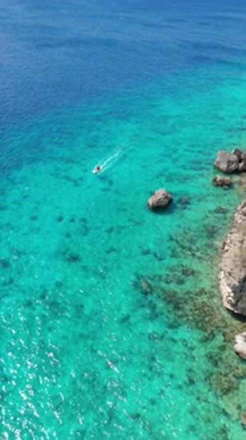Aerial drone footage showing a small boat driving close to cliff