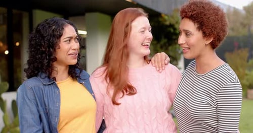 Three Cheerful Women Embracing Outside a Home
