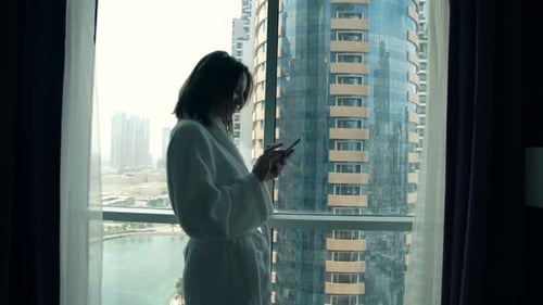 Woman in Bathrobe Using Tablet in City Apartment