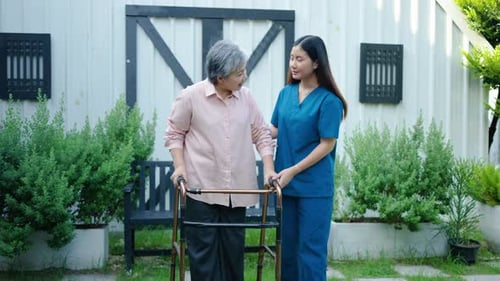 Doctor or nurse caregiver with senior asian woman using walker assistance at home or nursing home