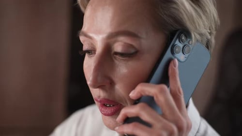 Closeup Face of Serious Middleaged Business Woman Having Work Call in Office Using Mobile Phone