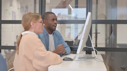 Workers Celebrate Success at Computer in Urban Office