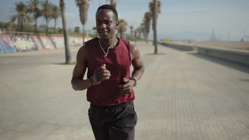 Young African Man Running Near the Beach and Training for Marathon Race