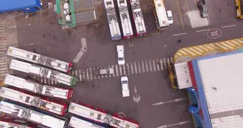 Overhead of three cars parked in the center of a bus station