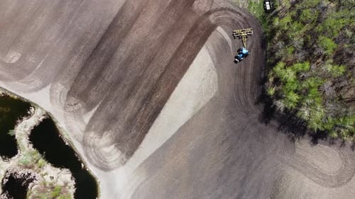 Aerial top down view rotating of a tractor plow tilling a field