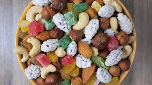 Sweets, raisin, candied fruit and nuts in a bowl rotating on a table. Close up view.