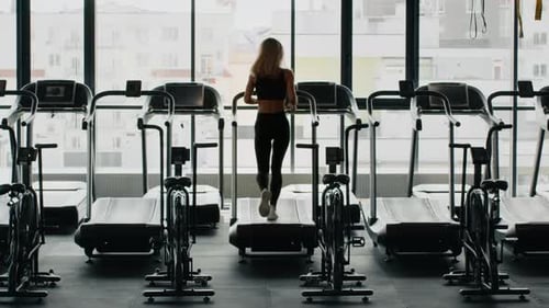 Back View of Unrecognizable Active Woman Practicing Cardio Workout Running on Treadmill at Gym