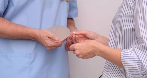 Doctor and Patient Exam Consultation in Clinic Office Holding Breast Enlargement Implant in Hands