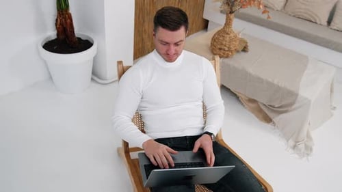 Handsome male in white shirt opens laptop and starts working. Top view on the entrepreneur freelanci