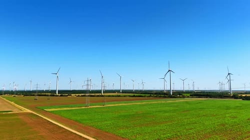 Footage over the field along the electricity power lines and wind farms.
