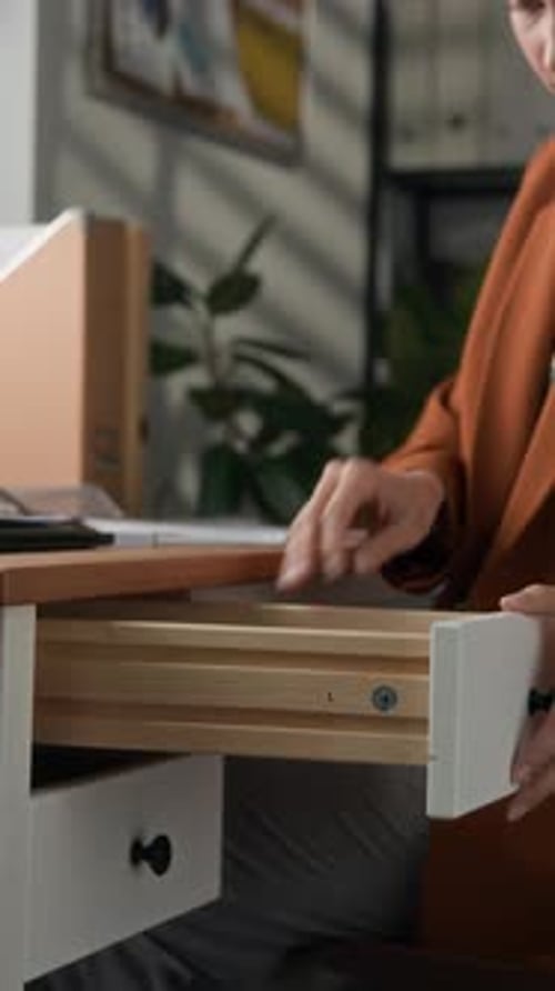 Female Office Worker Clamping Documents with Paper Clamp at Desk