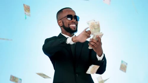 Happy businessman, money rain and celebration for lottery, investment or saving against a studio