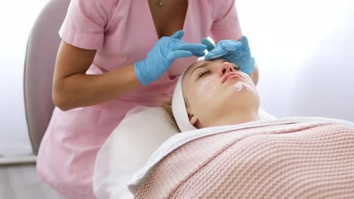Cosmetologist applies a moisturizer face cream, professional cosmetic procedure in a beauty clinic