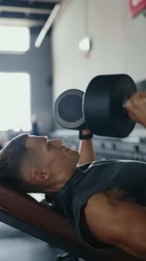 Young Man Doing Weightlifting Bench Press Exercise at the Gym