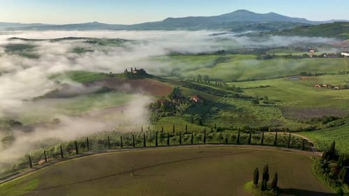 Aerial view of green rolling hills and fog, Tuscany, Italy.