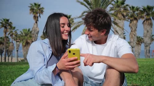 Smiling Couple Using Phone Together Outdoors