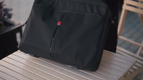 CloseUp of Woman Placing Bag on Wooden Table Outdoors