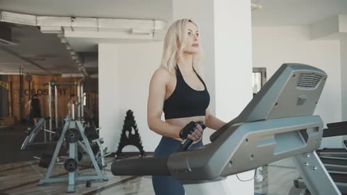 Girl working out on treadmill in gym with modern equipment and smooth slow motion captures