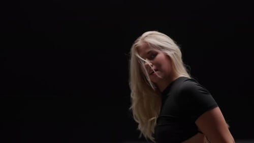 Séduisante jeune femme dansant en studio sur fond noir