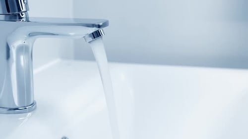 Water Flowing From Faucet into Sink