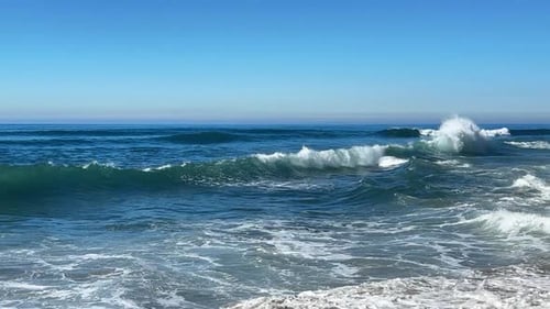 Las olas del océano chocan y se rocían juntas durante King Tide sobre el océano azul y el cielo azul.