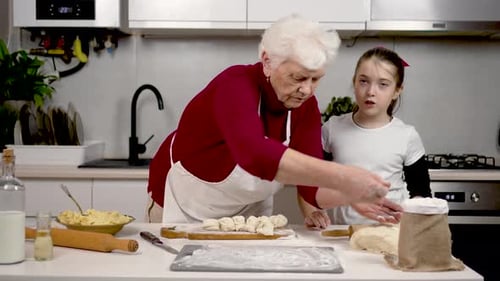 Schöne Familie, die zusammen Kuchen mit Füllung in der Küche kocht, Oma und Enkelin haben gute Laune